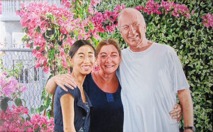 Trois personnes souriantes posent devant des fleurs colorées.