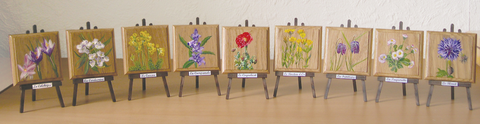 Tableau de peintures de fleurs sur petits chevalets en bois.