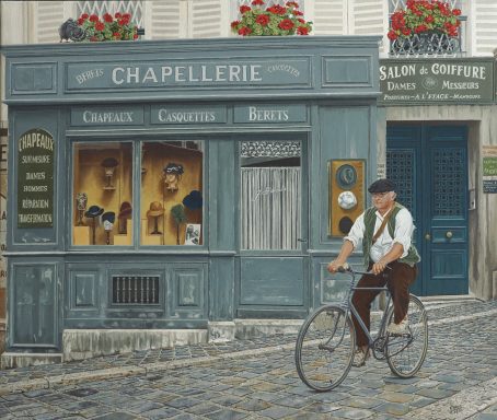 Un homme à bicyclette passe devant une chapellerie à Paris, avec des fleurs aux fenêtres.