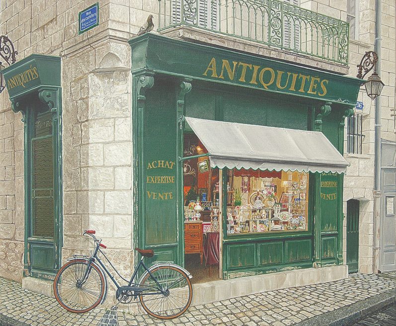 Boutique d'antiquités avec vitrine, enseigne verte et un vélo bleu garé devant.