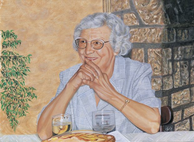 Femme âgée souriante, assise à table avec un verre et une tarte aux pomme.
