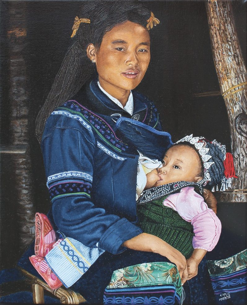 Femme en tenue traditionnelle tenant un bébé sur ses genoux.
