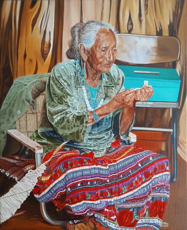 Femme âgée en costume traditionnel, assise, brodant et tenant un objet dans ses mains.