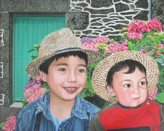 Deux enfants souriants portant des chapeaux en paille devant des fleurs colorées.
